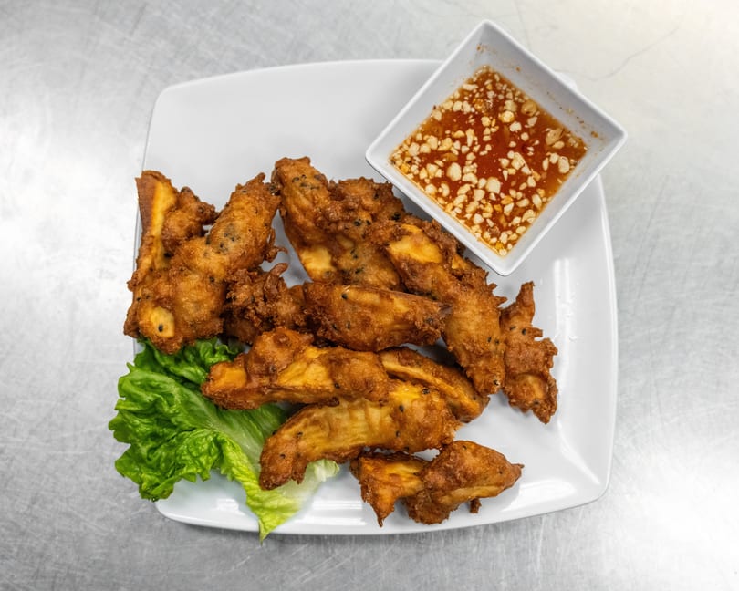 Crispy fried banana fritters with black sesame seeds, served with lettuce and a sweet chili dipping sauce.