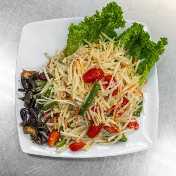 Som Tum, a Thai green papaya salad with cherry tomatoes, green beans, and small crabs.