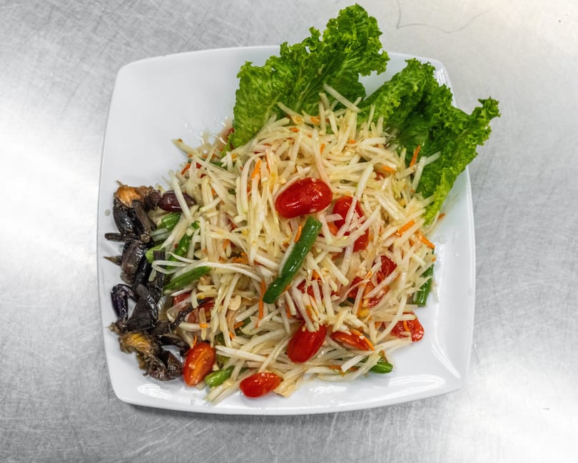 Som Tum, a Thai green papaya salad with cherry tomatoes, green beans, and small crabs.