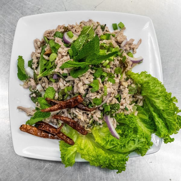 Larb Gai, a Thai dish with minced chicken, herbs, red onion, and dried chilies on lettuce.