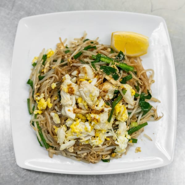 Crab Pad See Ew with scrambled egg, bean sprouts, green onions, and a lemon wedge.