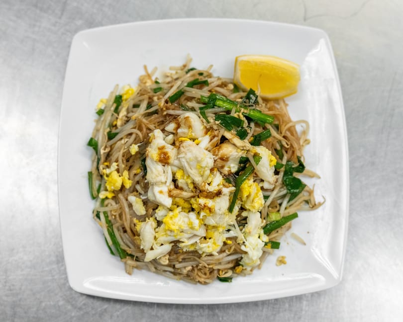 Crab Pad See Ew with scrambled egg, bean sprouts, green onions, and a lemon wedge.