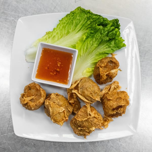 Crispy fried shrimp rolls with sweet chili sauce and fresh lettuce on a white plate.