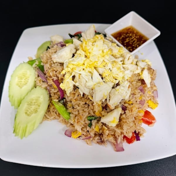 Crab fried rice with scrambled egg, cucumber slices, and a side of chili sauce.