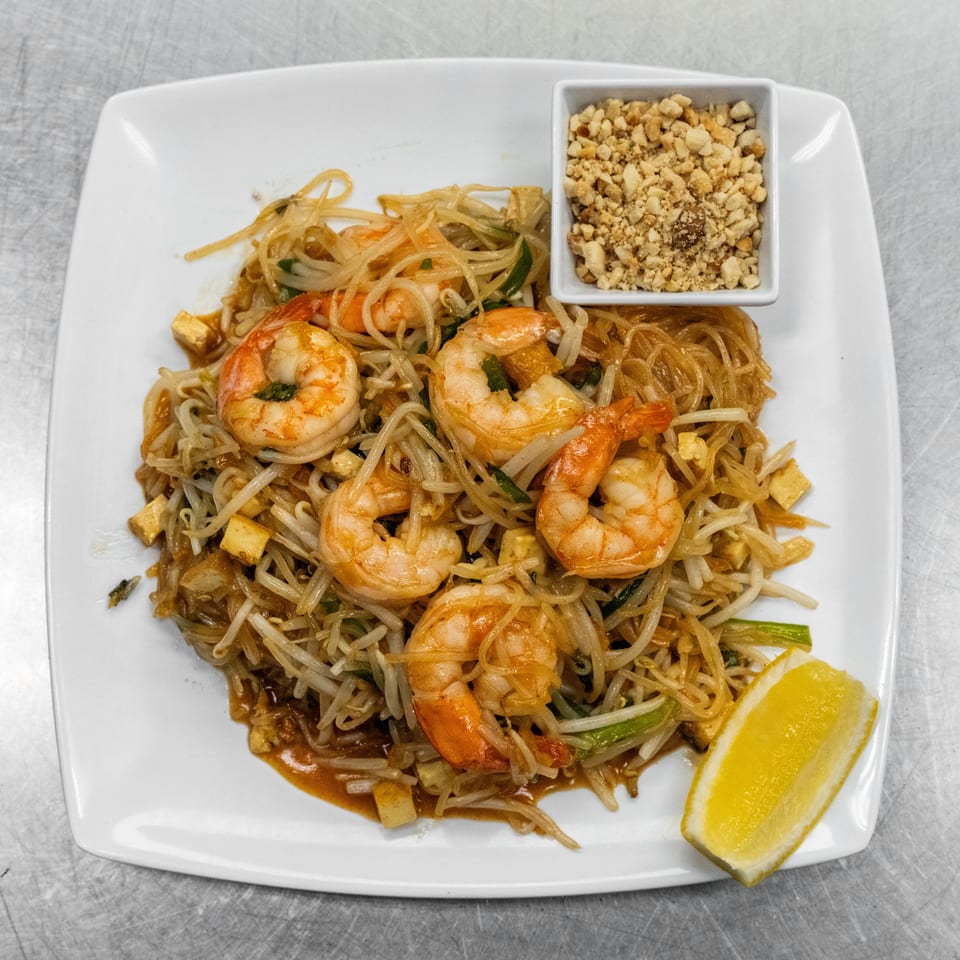 Shrimp Pad Thai with noodles, bean sprouts, tofu, crushed peanuts, and a lemon wedge.